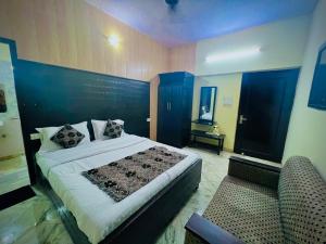 a bedroom with a large bed and a chair at Gaurav Boarding House in Mathura