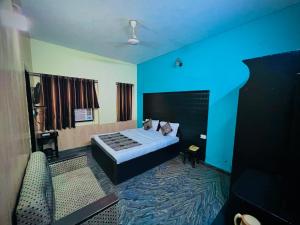a blue room with a bed and a couch at Gaurav Boarding House in Mathura