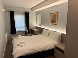 a bedroom with a bed with white sheets and a window at Harbour Mill Apartment in Westport