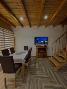 a dining room with a table and a flat screen tv at Vlasic Odmor - Villa Krajina III in Vlasic