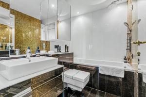 a bathroom with a white sink and a tub at Eurovea Apartments in Bratislava