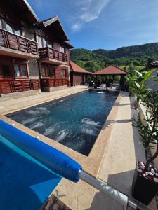 a swimming pool in front of a house at Apartmani ODMOR NA DRINI in Ljubovija