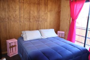 a blue bed in a room with a window at Kapai Departamentos de Turismo in Valdivia