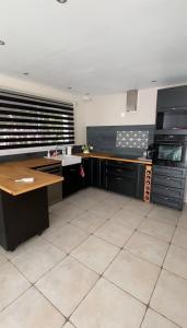 a kitchen with black cabinets and a white tile floor at Le clos des voies in Ganges