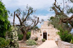 a stone building with a door and trees at Masseria La Vecchia Lamia in San Vito dei Normanni