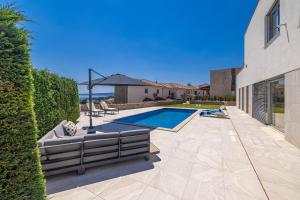 a swimming pool with a couch and an umbrella at Villa SIA with private pool in Krk
