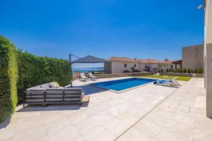 a swimming pool in a backyard with a couch and an umbrella at Villa SIA with private pool in Krk +42 photos