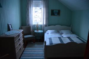a bedroom with a bed and a chair and a window at Skagakaia in Bø i Vesterålen
