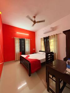 a bedroom with red walls and a bed and a table at Baylio Homestay in Kappil +3 photos