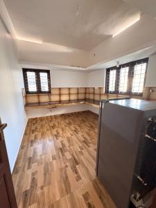 an empty room with wooden floors and windows at Baylio Homestay in Kappil