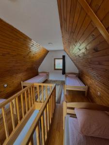 a room with three bunk beds and wooden ceilings at Vlasic Odmor - Villa Krajina II in Vlasic