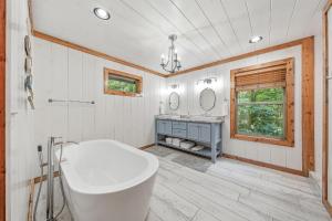 a bathroom with a tub and a sink and mirrors at Twilight Pines - Dreamy Cabin w Hot Tub & optional Kids Loft in Broken Bow +74 photos