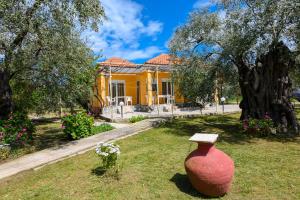a large vase sitting in the grass in front of a yellow house at Qyra Studios in Skala Rachoniou