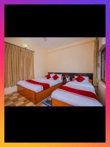 two beds in a hotel room with red pillows at Hotel Bien Venue in Pokhara
