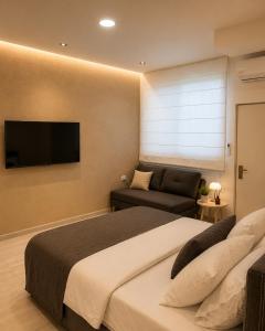 a bedroom with a bed and a couch and a television at Dizengoff Square Garden - by BAR COLLECTION in Tel Aviv