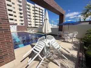 a patio with chairs and an umbrella and a pool at Condomínio Club Resort 2 quartos com ar na melhor da Aruana in Aracaju