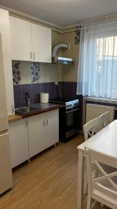 a kitchen with white cabinets and a table and a sink at Garden vibe apartament in Luduş