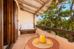 a table with glasses of orange juice on a balcony at Caprifogli Townhouse Close to the Beach in Baja Sardinia