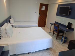 a room with two beds and a desk and a computer at HOTEL ROTA DO SOL in Praia Grande