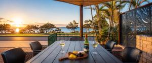 a wooden table with wine glasses and a plate of food at Blue Waters - Beachfront and River View - Sleeps 6 -Central Kalbarri in Kalbarri
