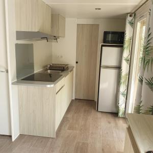 a kitchen with a white refrigerator and wooden cabinets at Camping de Bourges in Bourges +13 photos