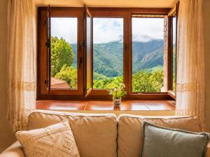 a couch in a living room with a large window at Casa Rural La Carrozal Senda del Oso in Orelleiru