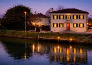 a house sitting next to a river at night at Romantic suite between Venice and Padua in Dolo