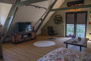 a living room with a television and a table at DuinDroom bovenappartement, Beverwijk in Beverwijk