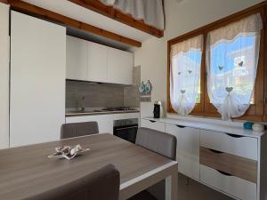 a kitchen with a wooden table and a kitchen with white cabinets at Villa Anna in Costa Rei