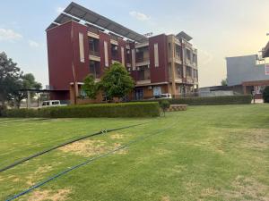 a red building with a grassy yard in front of a building at Amar mahal hotel and restaurant in Khātu +1 photo