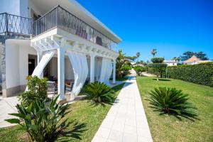 a white house with a balcony and a lawn at Villa Fontane Bianche in Fontane Bianche