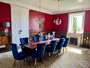 a dining room with a table and blue chairs at Chateau Mas Levrault in Saint-Priest-Taurion