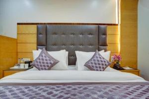 a bedroom with a large bed with purple and white pillows at Hotel Urban ECG Grand - Inn Near IGI Delhi Airport in New Delhi