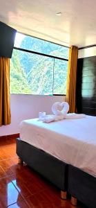 a bed in a room with a large window at Hostal Mónaco in Machu Picchu