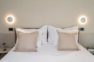 a white bed with white pillows on it at Hotel Estense in Gatteo a Mare