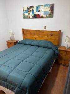 a bed with a blue comforter in a bedroom at Casa El Manantial in Vallenar