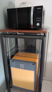 a microwave oven sitting on top of a shelf with a box at Chambre studio in Sublaines