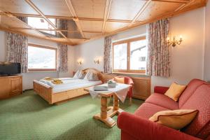 a hotel room with a bed and two chairs at Pension Cafe Fritz in Lech am Arlberg