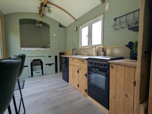 a kitchen with wooden cabinets and a black stove at Kingfisher Shepherd's Hut in Saint-Mars-sur-la-Futaie +29 photos