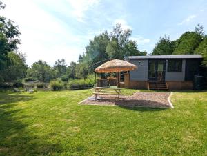 a small shed with a picnic table in a yard at Kingfisher Shepherd's Hut in Saint-Mars-sur-la-Futaie