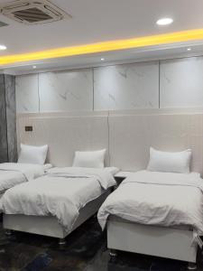 three beds in a room with white walls at الربيعي للشقق الفندقية 200متر عن الحرم in Karbala