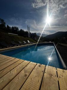 a swimming pool with a wooden deck and the sun at Zrub House in Slavske