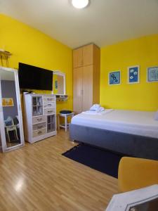 ein Schlafzimmer mit einem Bett und einem Fernseher und gelben Wänden in der Unterkunft Sun Garden in Čitluk