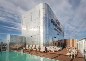 a building with chairs and a swimming pool on a roof at Puerto Norte Design Hotel in Rosario