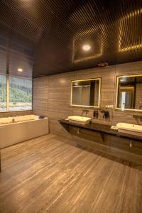 a bathroom with two sinks and a mirror and a tub at Asal Riverside Pahalgam in Pahalgām