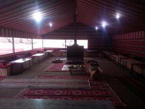 a large room with tables and chairs and rugs at Wadi rum Local guide camp in Wadi Rum