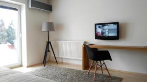 um quarto com uma televisão na parede e uma cadeira em Villa Green em Sliac