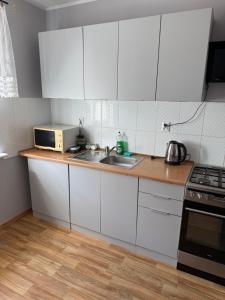 a kitchen with white cabinets and a sink and a microwave at Daniel Apartment in Reda