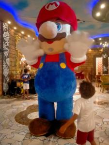 a young child standing next to a large balloon of mickey mouse at غرفتين و ترأس بالاندلسية in Marsa Matruh