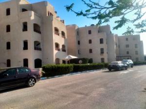 a row of white buildings with cars parked on the street at غرفتين و ترأس بالاندلسية in Marsa Matruh